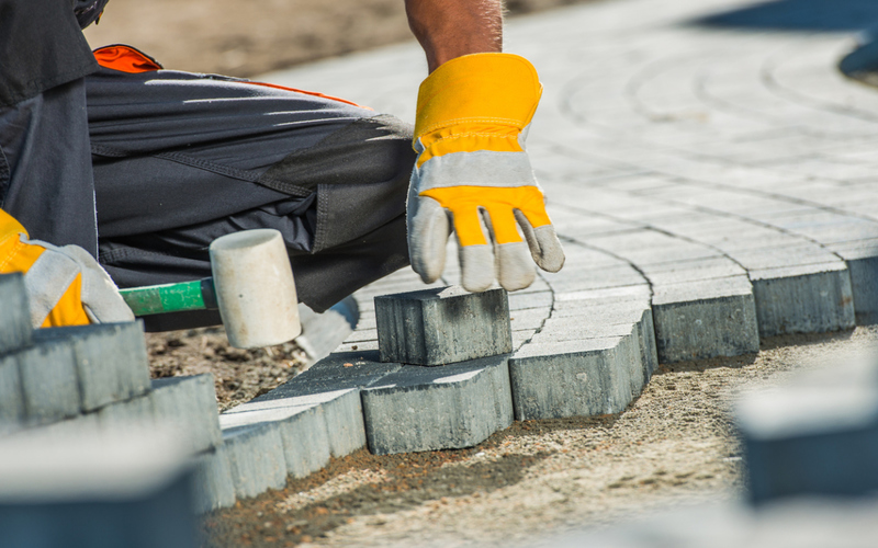 Brock Paving Closeup Photo. Construction Worker Paving Brick Pathway.